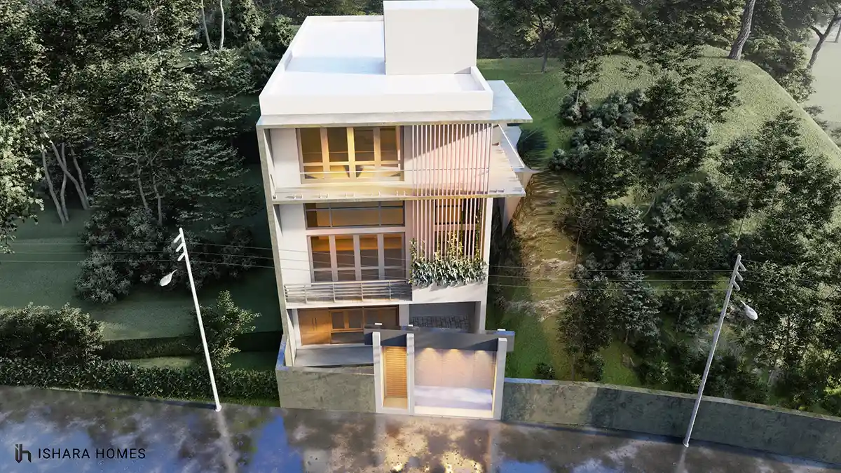 An aerial view shows the home tucked into its sloped, tree-lined plot, its flat white rooftop and stacked balconies overlooking a quiet drainage...
