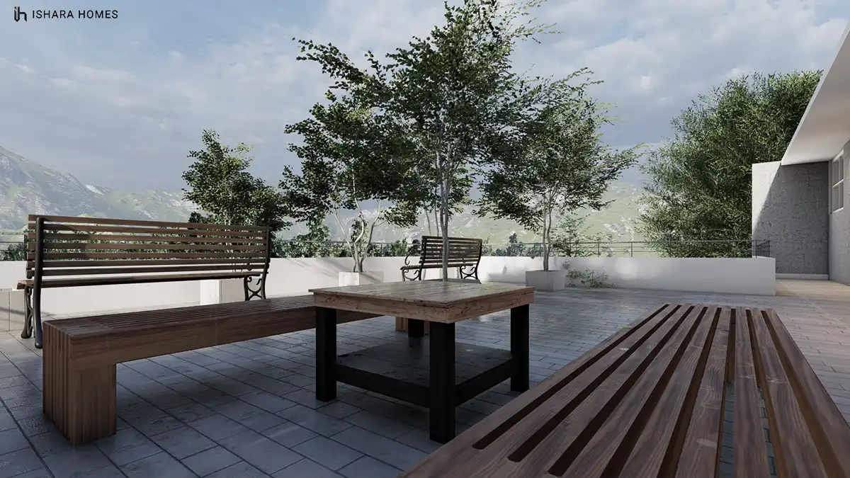 On the rooftop terrace, weathered timber benches and a table cluster beneath young trees, with the misty hillside estate's namesake mountains...
