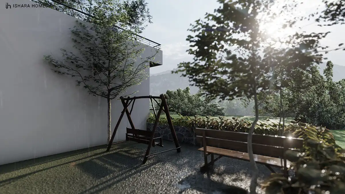 In a shaded corner of the garden, a wooden swing seat and bench sit on gravel paving beneath young trees, with hazy hills and a stacked-stone...
