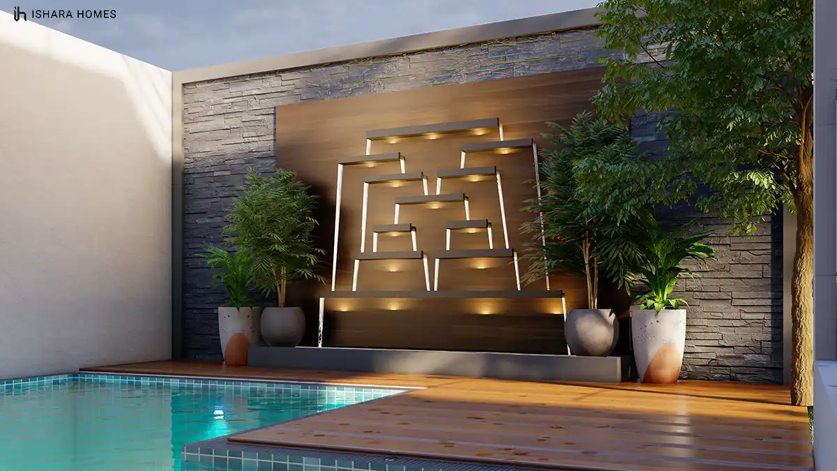 A backlit stacked-stone water feature cascades gently beside the pool deck, its warm downlights and potted ferns creating a spa-like corner of the...