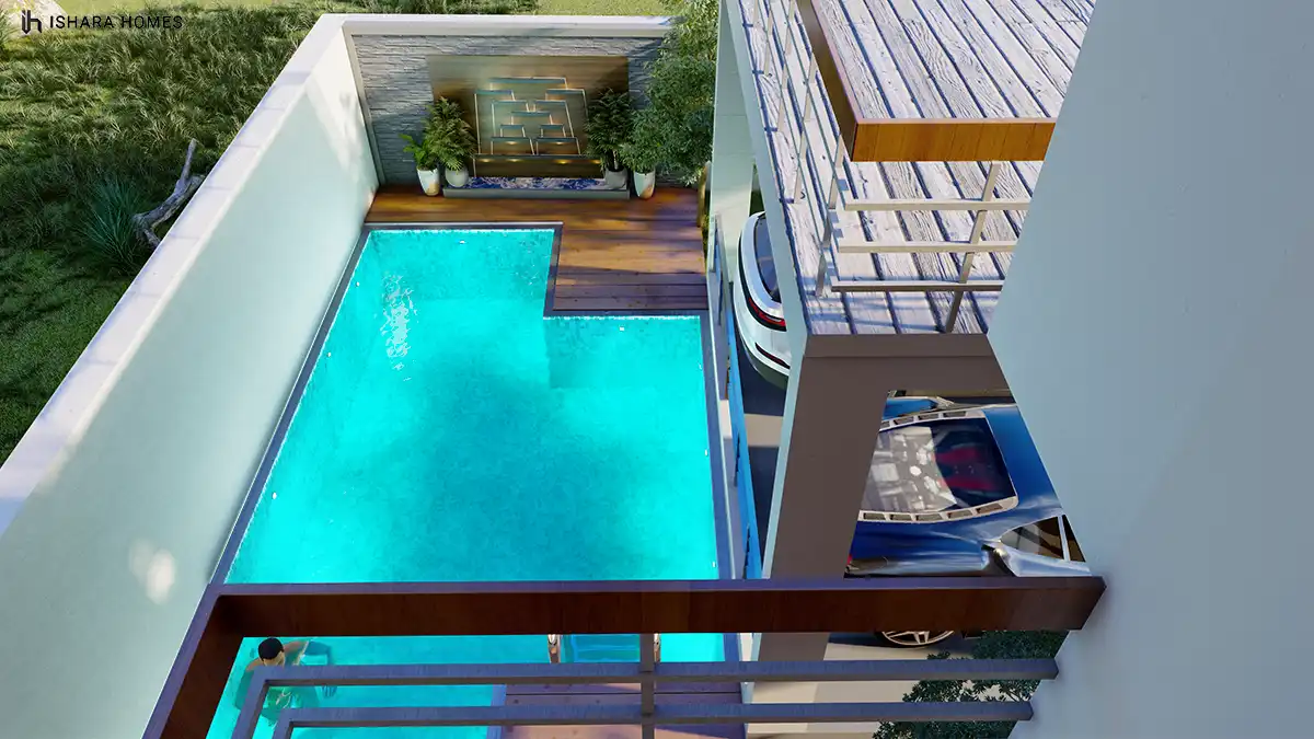 Viewed from the balcony above, the L-shaped pool reveals its full layout beside the timber sun deck and the illuminated stone feature wall, with...