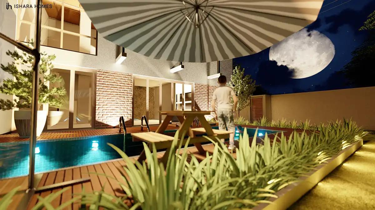 A night view of the pool terrace with a full moon rising over the boundary wall, the picnic table and lit pool creating a quiet evening gathering...