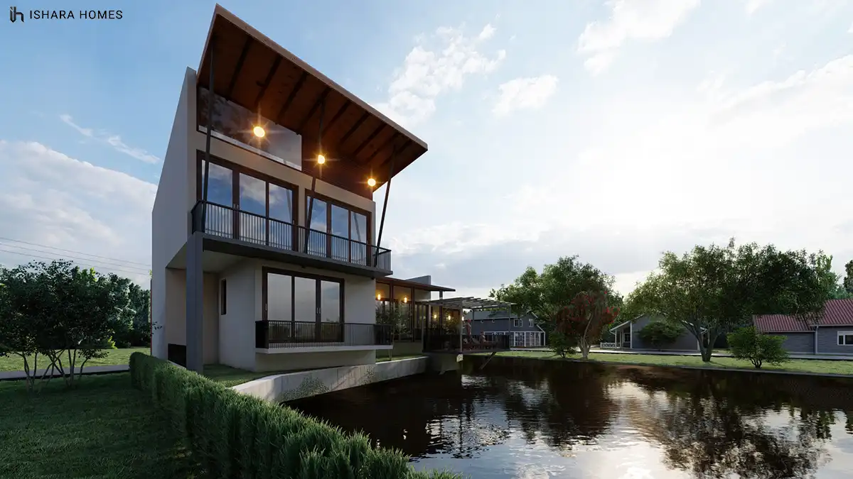 A twilight view of the water-facing corner captures the tall glazed facade and covered balcony glowing with pendant lighting, set beside the still...